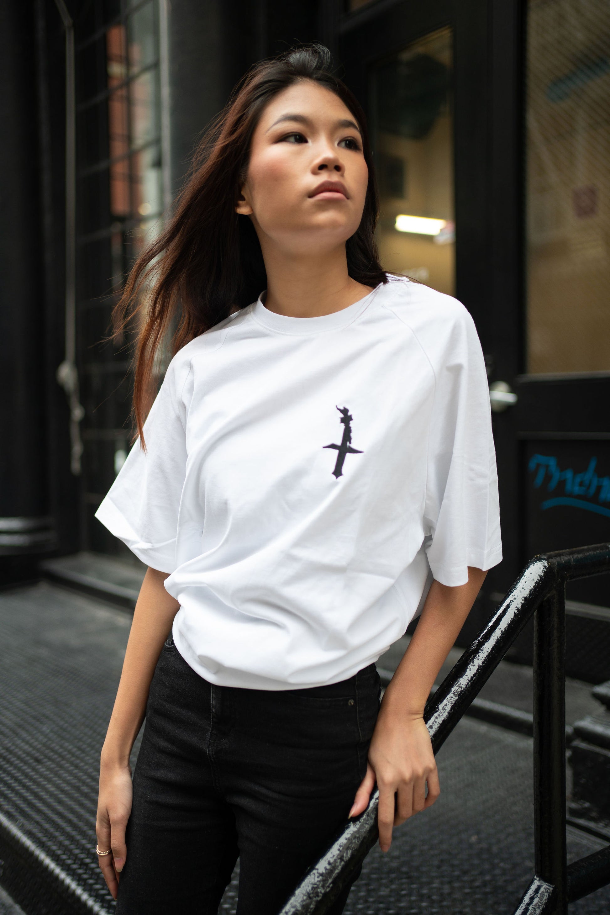 Oversized white t-shirt, heavyweight and 100% cotton. Black embroidered BITA Torch on left chest, grey jock tag with black born in the apple text on bottom left edge, and black screen printed Born In  The Apple text covers the back. Raglan sleeves. 