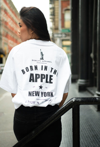 Oversized white t-shirt, heavyweight and 100% cotton. Black embroidered BITA Torch on left chest, grey jock tag with black born in the apple text on bottom left edge, and black screen printed Born In  The Apple text covers the back. Raglan sleeves. 